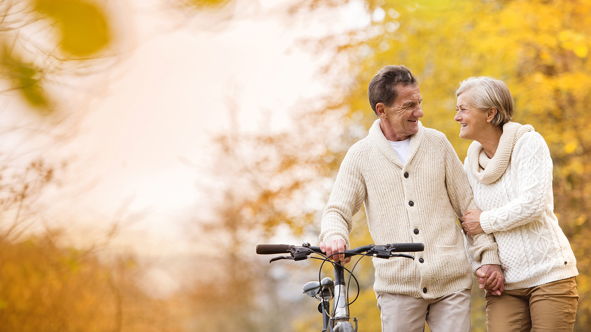 Older couple walking with a bike in the countryside.