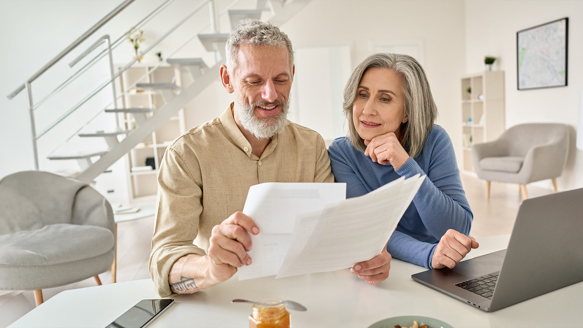 Older couple in their home looking at paperwork weighing out retirement options.