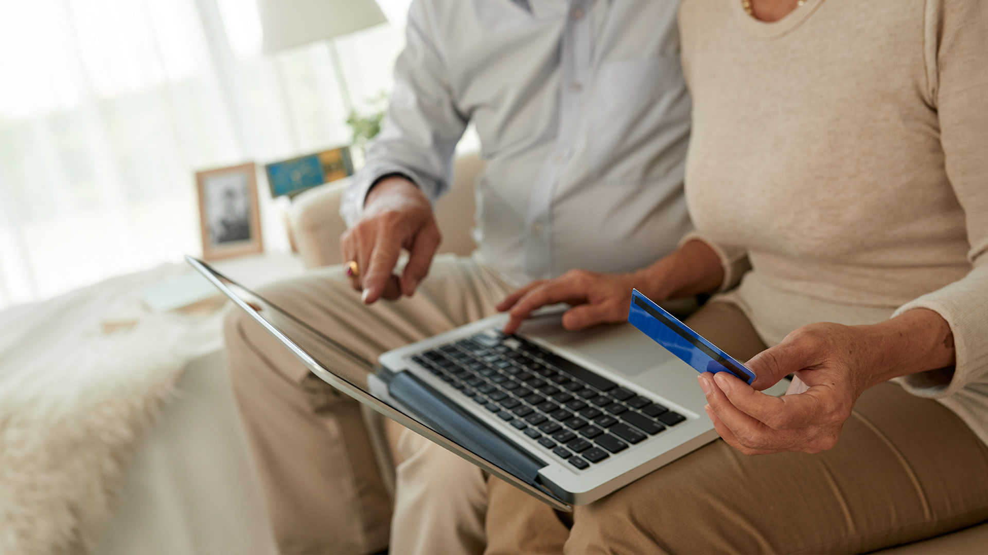 Older couple pointing at laptop holding credit card.