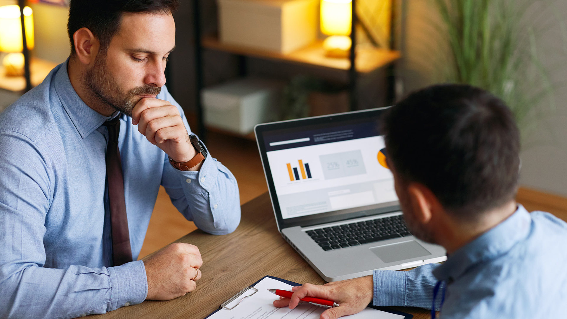 Two businessmen sat at a meeting with a laptop.