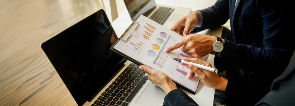 Hands pointing to charts on a clip board.