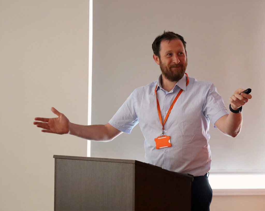 Reeves member of staff presenting at a meeting holding a pointer.