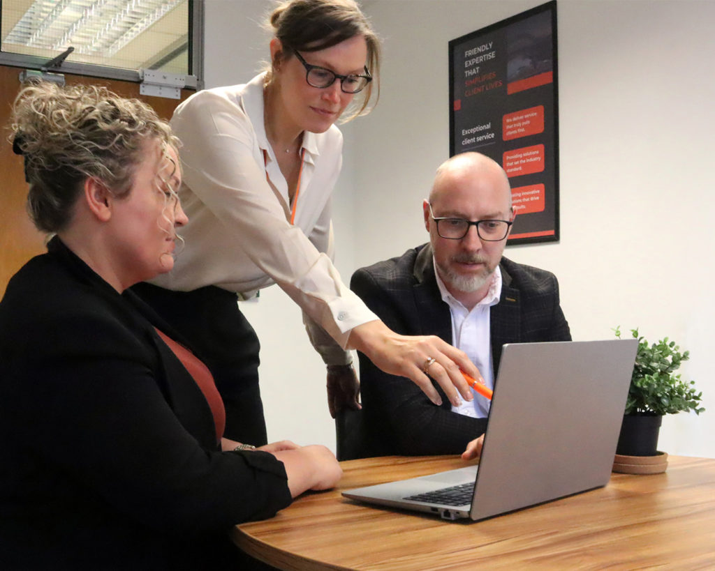 Reeves member of staff pointing at laptop screen with two clients.